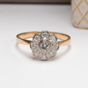 Elegantti 18K kultainen kukkasormus, jossa 0,13 ct briljantti ja 8 timanttia (yht. 0,24 ct). Valmistaja Kultakeskus Oy, Hämeenlinna 1992.