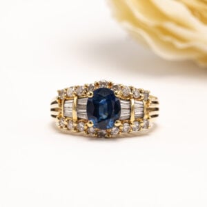 18 karaatin keltakultainen safiirisormus, jonka keskiössä loistaa ovaali viistehiottu sininen safiiri.