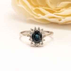 Valkokultainen safiiri- timanttisormus, jossa Dianasormus tyylinen klassinen kukkakehä tuo koruun arvokkuutta ja ajattomuutta.