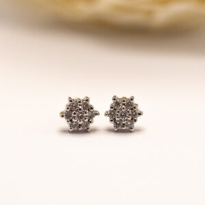 valkokultaiset timanttikorvakorut briljanttihionnalla. Kukkamainen muoto ja tiivis kiviasettelu luovat säihkyvän kokonaisuuden.