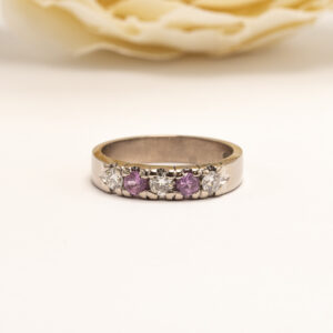 valkokullasta valmistettu sormus on tasapainoinen kokonaisuus, jossa kirkkaat timantit ja pinkit safiirit muodostavat harmonisen rytmin.