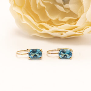 Korujen keskiössä ovat kaksi cushion-muotoon viistehiottua sinistä topaasia (yht. 3,30 ct), joiden kirkas ja eloisa sävy heijastaa valoa kauniisti.