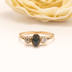 Kaunis 18 karaatin keltakultainen sormus, jossa klassinen kolmen kiven asettelu korostaa jalokivien keskinäistä tasapainoa.