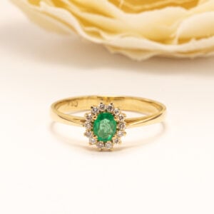 Sormuksen keskellä on ovaali viistehiottu smaragdi (0,20 ct), jonka kirkas vihreä sävy antaa korulle raikkaan ja elävän ilmeen.