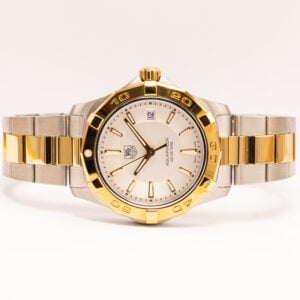 TAG Heuer Aquaracer 300 m kvartsikello. Terästä ja keltakultaa, hopeinen taulu ja päivyrinäyttö. Tyylikäs ja luotettava sveitsiläinen rannekello.