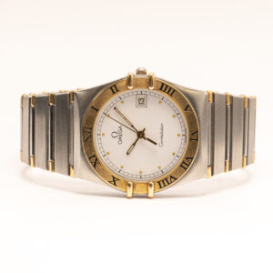 Omega Constellation on yksi sveitsiläisen Omegan tunnetuimmista ja arvostetuimmista kellomallistoista. Vuonna 1952 esitelty Constellation saavutti mainetta tarkkuudestaan ja korkeatasoisesta kellonvalmistuksestaan. Malliston tunnistettava muotokieli uudistui 1980-luvulla, jolloin esiteltiin Constellation Manhattan -malli. Sen tunnusmerkeiksi muodostuivat roomalaisin numeroin koristeltu kehä, kuoren sivuilla olevat neljä kiinnityskynttä sekä saumattomasti kuoreen liittyvä metalliranneke. Tässä klassisessa Omega Constellation -rannekellossa on 32 mm:n teräskuori, jota täydentävät kullanvärinen kehä ja yksityiskohdat. Vaaleassa kellotaulussa on sirot kullanväriset pisteindeksit ja osoittimet, jotka luovat kauniin vastakohdan kellon kaksiväriselle kuorelle. Päivämääränäyttö sijaitsee perinteisesti kello kolmen kohdalla. Kokonaisuuden viimeistelee teräksen ja kullan sävyjä yhdistelevä metalliranneke. Kellossa on tarkka ja helppokäyttöinen kvartsikoneisto. Constellation-mallistolle ominaiset roomalaiset numerot, kiinnityskynnet ja integroitu ranneke tekevät kellosta helposti tunnistettavan Omega-klassikon. 32 mm:n kuorikoko tarjoaa perinteistä naistenkelloa hieman näyttävämmän vaihtoehdon, joka sopii erinomaisesti niin arkeen kuin juhlavampaan pukeutumiseen.